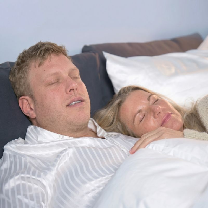 Par sover fredeligt i seng, kvinde hviler hovedet på mandens bryst
